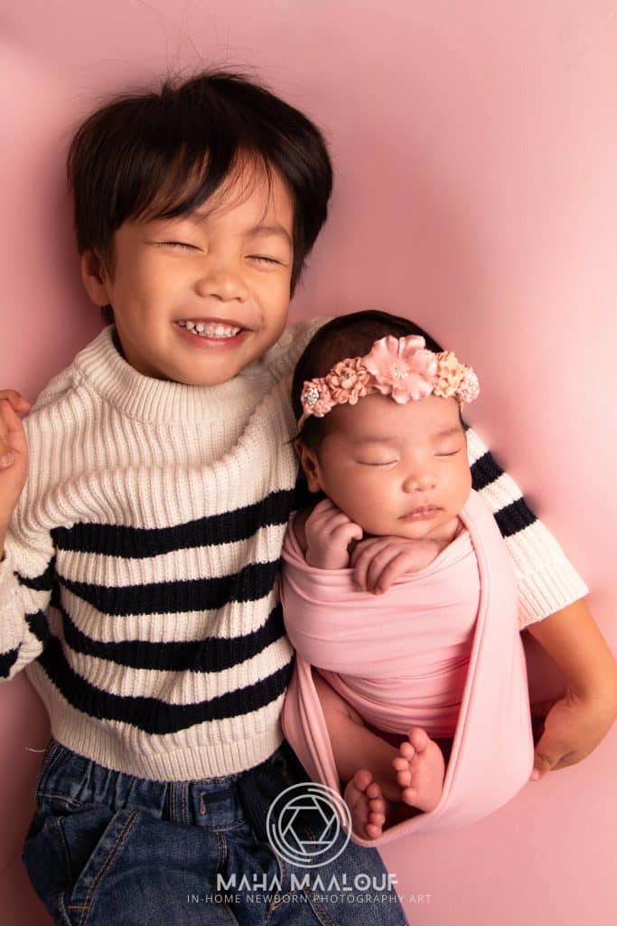 Older sibling holding newborn baby during family photo session
