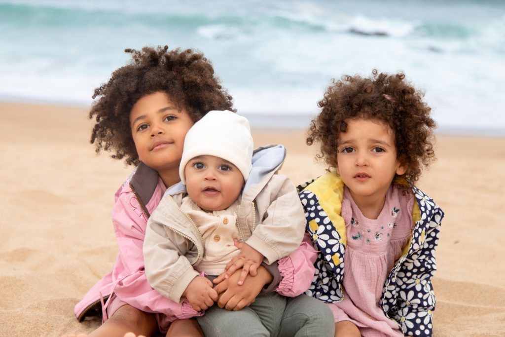 Three children sitting together during an outdoor family photography session