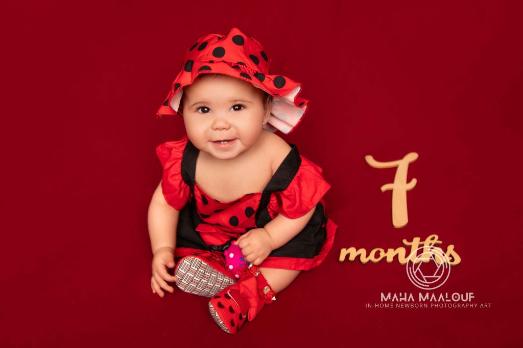 Seven-month-old baby in a red ladybird outfit during monthly baby photography in Lisbon