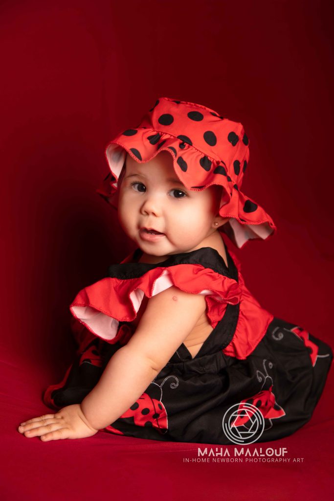 Baby in a red ladybird outfit during a milestone photography session