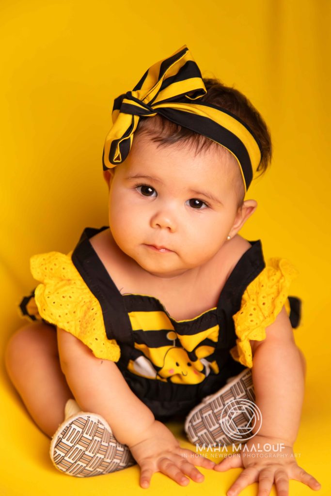 Baby in yellow outfit during an at-home monthly baby photoshoot