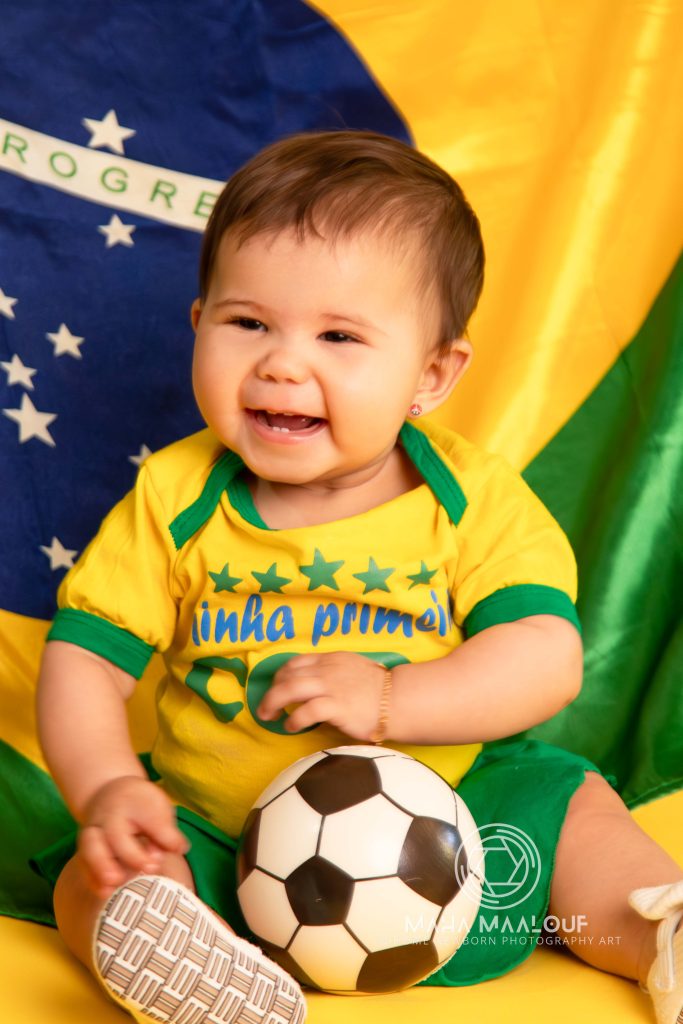 Smiling baby with football during a monthly baby photography session