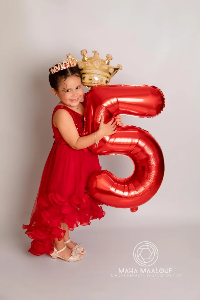 Menina com balão número cinco numa sessão de aniversário