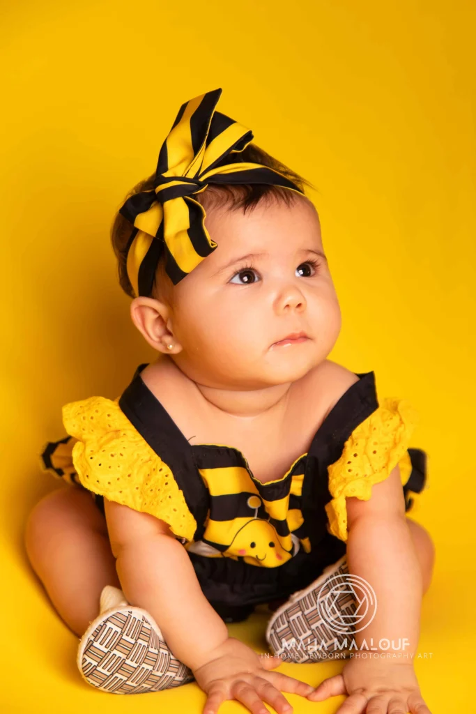 Retrato de bebé sobre fundo amarelo durante sessão fotográfica mensal