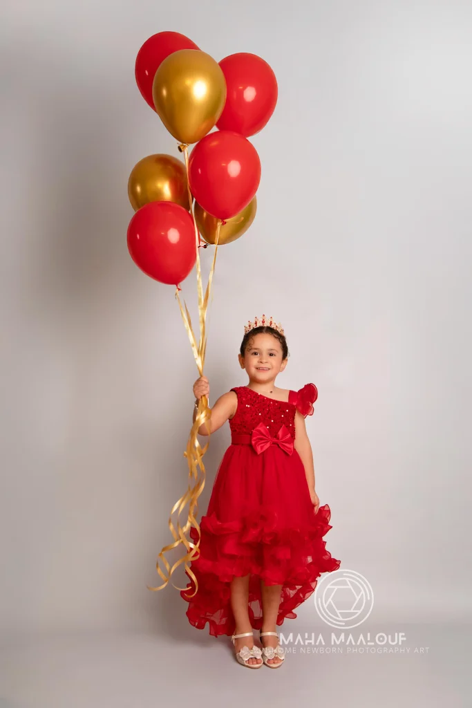 Menina com balões vermelhos e dourados em sessão de aniversário