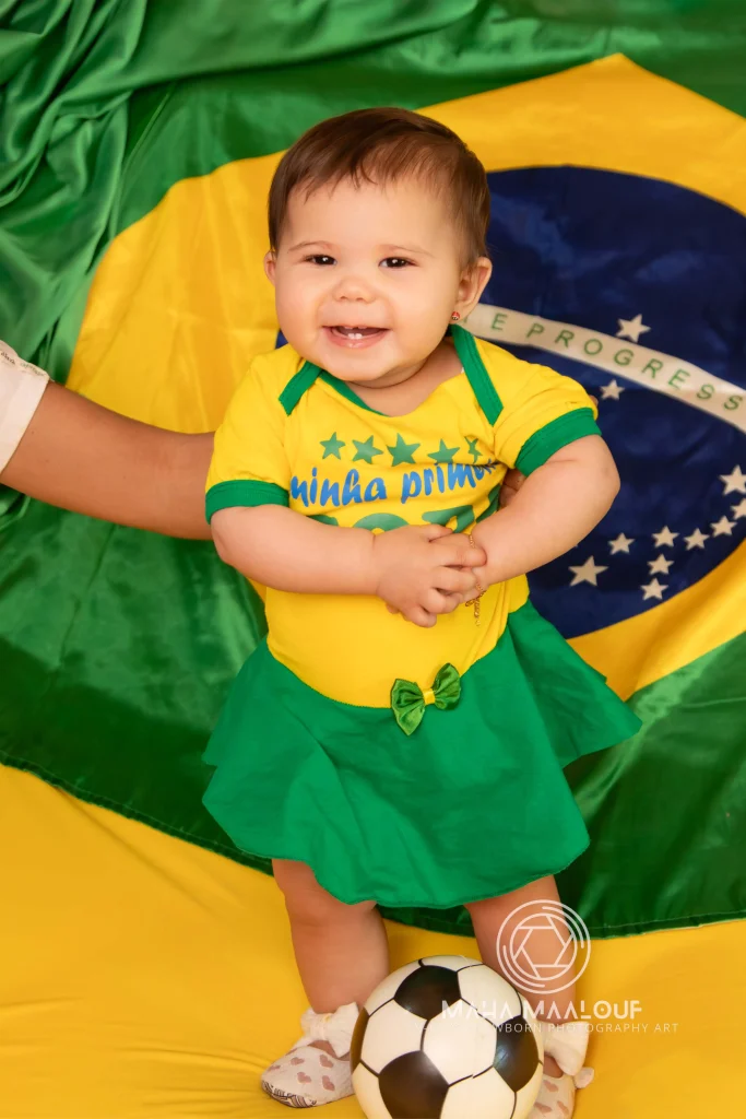 Bebé sorridente com bola durante sessão de fotografia mensal de bebé