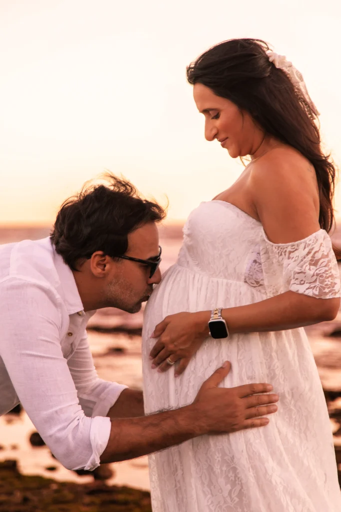Couple during a maternity photography session at sunset on the beach