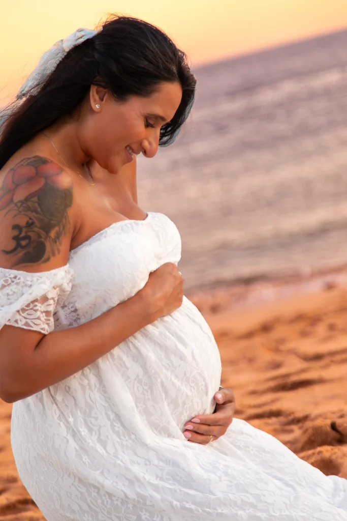 Pregnant woman in a white dress during a beach maternity photoshoot
