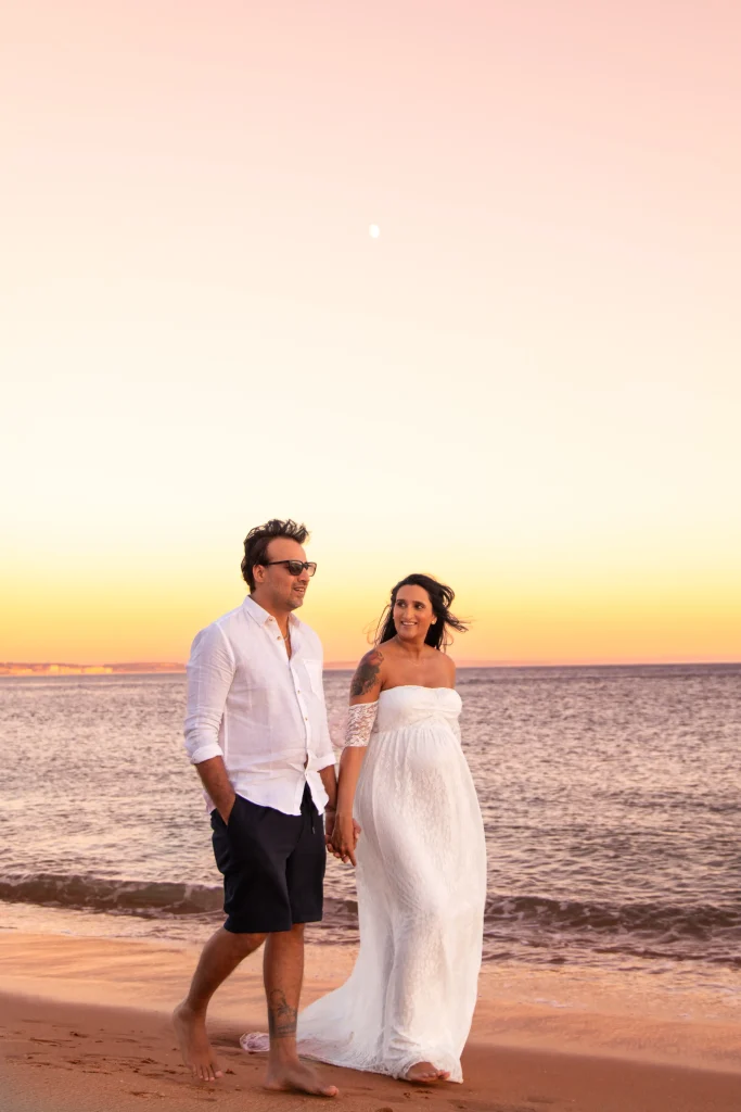 Expectant couple walking together during a sunset maternity session