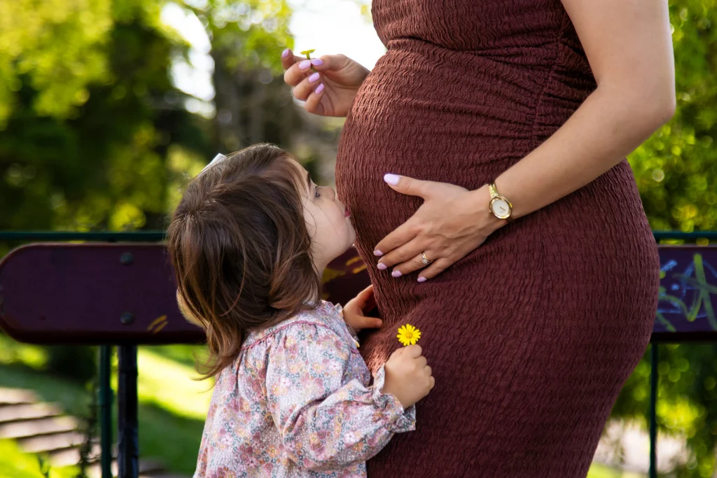 Child kissing her mother's baby bump during a maternity session