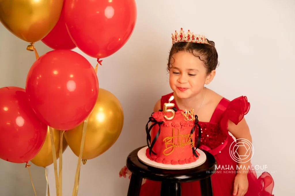 Menina com bolo e balões numa sessão de aniversário